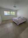 Neutral interior space featuring large-format ceramic tile flooring, horizontal window blinds, and a central semi-flush mount light fixture