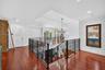 An impressive, second floor Landing overlooks the grand foyer below, showcasing, beautiful hardwood floors, decorative rod, iron railings, and strikin