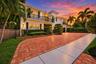 Two-story exterior featuring 2 car garage, circular drive, black balcony railings, a herringbone-patterned brick driveway, manicured landscaping, and 