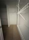 Walk-in storage area featuring multi-level white wire shelving and neutral tile flooring