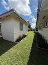 Exterior side yard featuring stucco finish, dedicated storage structure, manicured lawn, and defined landscape beds
