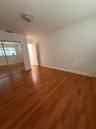 Room featuring wood-finish flooring, sliding mirror-panel closet doors, and a paneled interior door