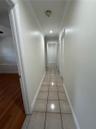 Hallway featuring ceramic tile flooring, recessed lighting, and built-in louvered closet doors
