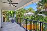 An expansive covered balcony of the primary suite offers a beautiful Tropical escape, surrounded by swaying palms and lush greenery with generous spac