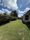 Rear yard featuring a manicured lawn, established landscaping, and a covered patio area