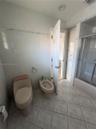 Bathroom featuring neutral tile wall wainscoting with decorative accent trim, floor-to-ceiling built-in cabinetry, and a shower-tub combination with a