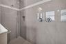 Floor-to-ceiling custom tilework and an accent detail wall give the walk-in shower a striking, spa-like feel.