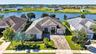 An aerial drone view highlights the front exterior of the home, framed by a serene lake backdrop.