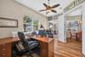 Framed by serene lake views, this dedicated home office features sliding glass doors that step directly out onto the lanai for an inspiring indoor-out