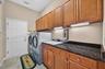 Equipped with rich granite counters, a built-in utility sink, and abundant cabinet storage, this interior laundry room doubles as a convenient drop zo