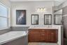 Dual vanity sinks and generous wood cabinetry provide abundant storage and counter space for effortless morning routines.