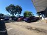 Paved exterior lot featuring a metal roof overhang and mature trees