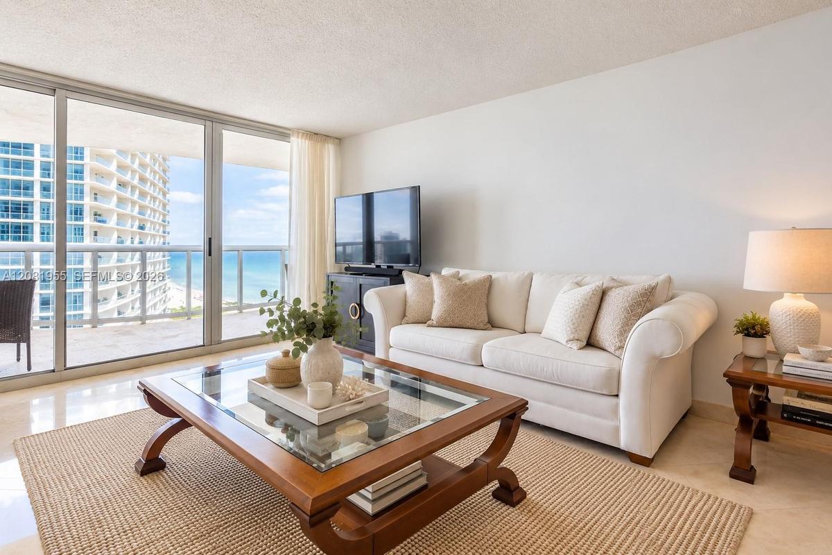 Floor-to-ceiling glass sliding doors, neutral stone flooring, and expansive exterior balcony. AI