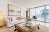 Living area featuring polished stone flooring and floor-to-ceiling glass sliding doors opening to a spacious balcony