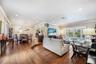 Open living room with wood-finish tile flooring, recessed lighting, crown molding, and impact glass French doors.