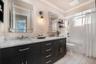 Hallway Bath. Double vanity featuring dark cabinetry, stone-finish countertops, lighted dual mirrored cabinets, wall-mounted lighting, and a bathtub-s
