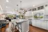Chefs kitchen featuring white shaker-style cabinetry, industrial pendants, a central island with granite.