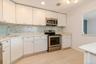 Kitchen with light countertops, white cabinets, visible vents, stainless steel appliances, and a sink