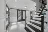 Foyer featuring high-gloss tile flooring, wainscoting, glass-panel entry door, sliding barn-style door with inset mirror, and staircase with glass rai