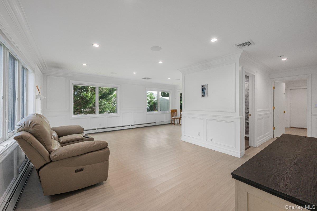 First Floor Bedroom featuring wood-finish flooring, white wall paneling, recessed lighting, and multi-pane windows and en-suite bathroom