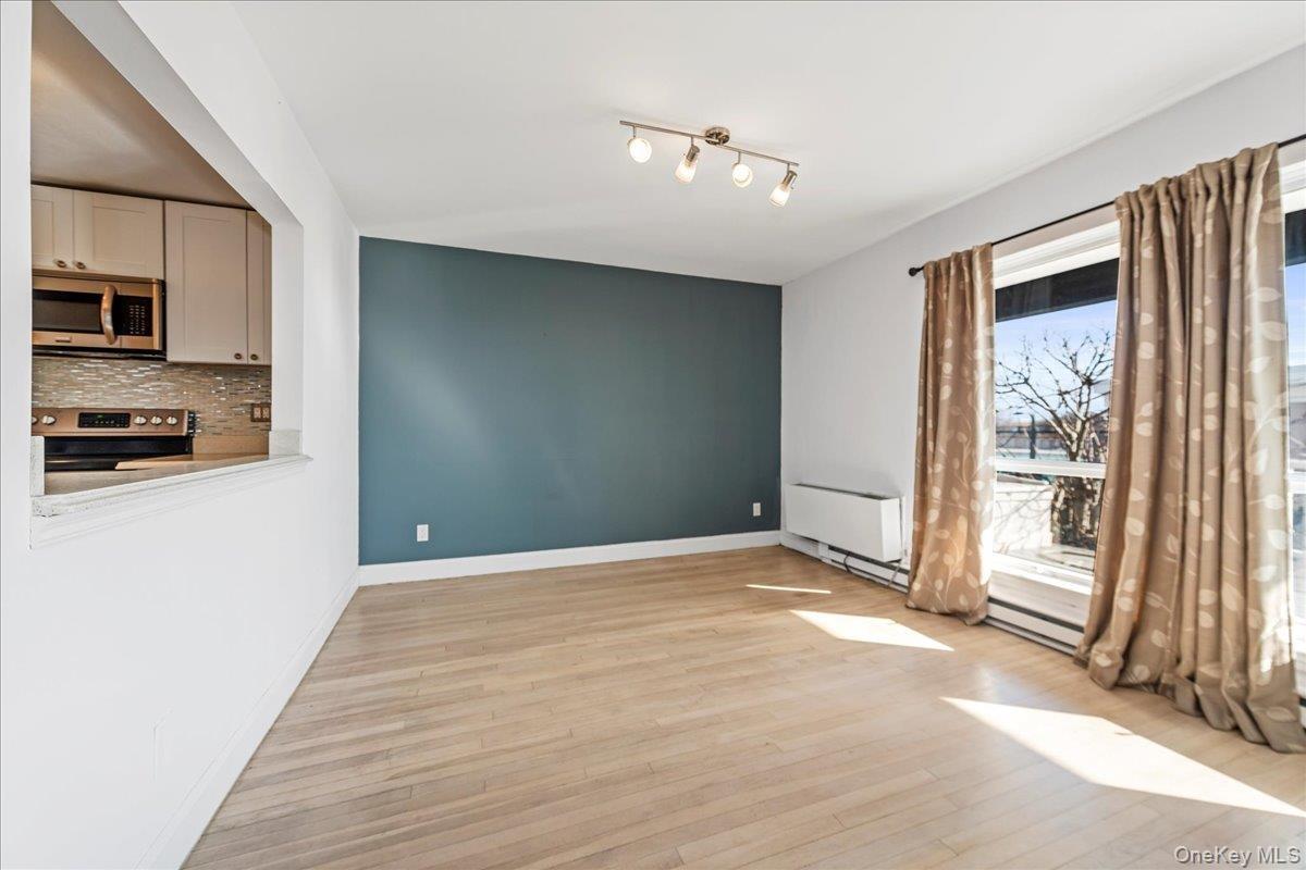 Unfurnished dining area featuring light wood-style flooring and baseboards