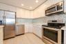 Kitchen featuring appliances with stainless steel finishes, a sink, light countertops, and white cabinetry