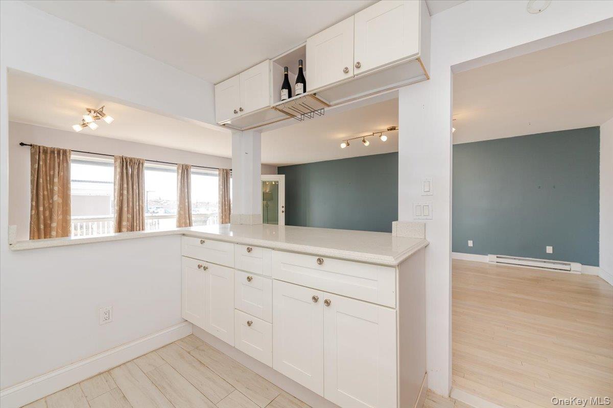 Kitchen featuring baseboard heating, white cabinetry, baseboards, and light countertops