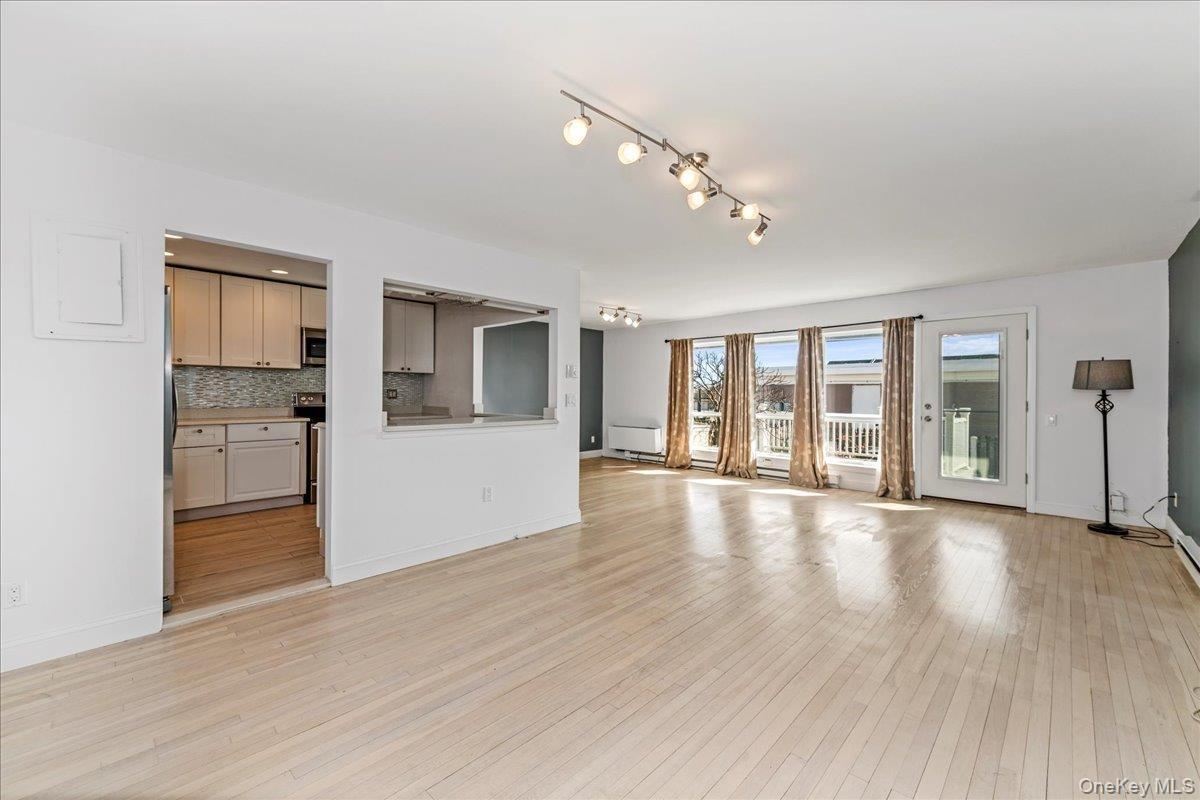 Unfurnished living room featuring light wood finished floors and baseboards