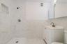 Bathroom featuring tiled shower, vanity, visible vents, and toilet