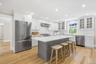 Kitchen features oversized island with Quartz countertops and backsplash, custom cabinets with wood insert details, Bosch appliances.
