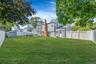 Expansive backyard featuring a fenced perimeter, brick chimney, and a detached storage shed