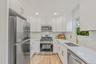 Kitchen featuring white shaker-style cabinetry, stainless steel appliances, light-toned quartz counters