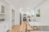 Kitchen featuring white shaker-style cabinetry, wood-finish flooring, stainless steel appliances, stone-look countertops, and recessed lighting