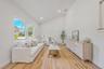Living room with vaulted ceilings, wood-finish flooring, recessed lighting, and large windows