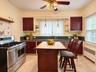 Kitchen featuring solid-color cabinetry, stone-finish countertops, professional-grade stainless steel range, ceramic-tiled kitchen island, and ceramic