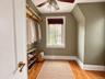 Custom wooden closet rod, wood-finish flooring, multi-pane window with white casing, and ceiling-mounted light fixture