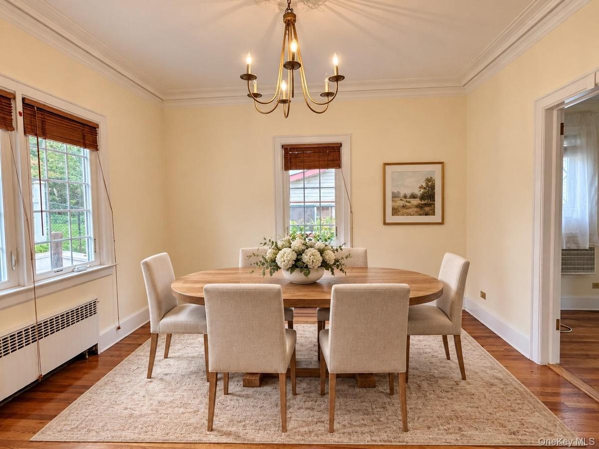 Dining area featuring wood-finish flooring, crown molding, and a multi-arm metal chandelier