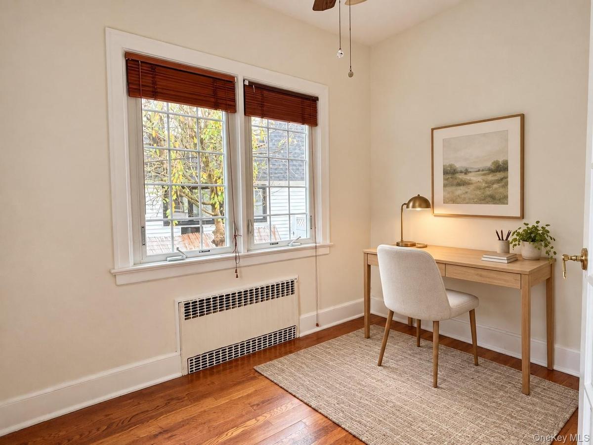 Wood-finish flooring, dual-pane windows with grid detailing, and recessed wall-integrated heating unit