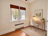Wood-finish flooring, dual-pane windows with grid detailing, and recessed wall-integrated heating unit