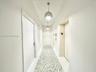 Hallway featuring crisp white walls, large-format tile flooring with a patterned mosaic inlay, and dual spherical pendant lighting fixtures