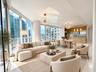 Floor-to-ceiling glass windows, open-concept layout, modern sputnik-style chandeliers, kitchen island with built-in cabinetry, and polished neutral fl