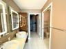 Dual floating vanity with rectangular vessel sinks, LED-backlit mirrors, wood-finish cabinetry, and porcelain tile flooring