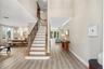 Open-concept interior featuring wood-finish flooring, a grand staircase with decorative metal balusters and wood handrails, high ceilings, recessed li