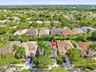 Aerial perspective featuring a two-story residence with a concrete tile roof, integrated swimming pool, attached multi-car garage, and mature palm tre