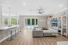 Open-concept living space featuring wood-finish flooring, recessed lighting, a built-in entertainment center, a kitchen island with stone-surface coun