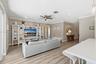Living area featuring wood-finish flooring, white built-in cabinetry, crown molding, a ceiling fan, and recessed lighting