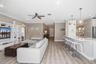 Open-concept interior featuring wood-finish flooring, built-in cabinetry, recessed lighting, and a breakfast bar with stone-surface countertops and pe