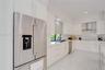 Kitchen featuring high-gloss white cabinetry, quartz countertops, stainless steel appliances, herringbone tile backsplash, and polished porcelain floo