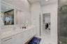 Double vanity featuring white cabinetry, quartz countertops, integrated under-mount sinks, and an expansive wall-to-wall mirror with under-cabinet lig