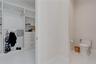 Custom walk-in closet featuring white built-in shelving and integrated drawer storage, paired with an enclosed water closet finished with stone-tile f